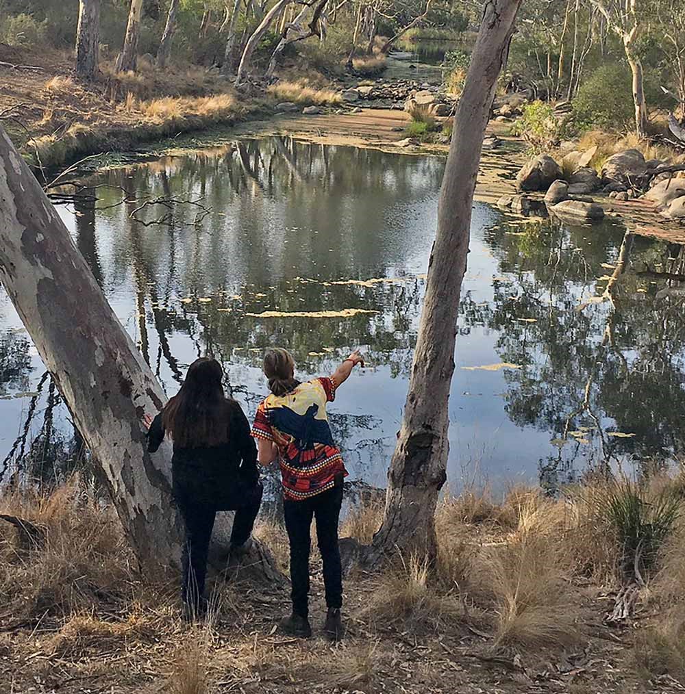 A photo of two Wadawurrung women standing next to the Moorabool River. Melinda Kennedy is on the left and Tammy Gilson is on the right