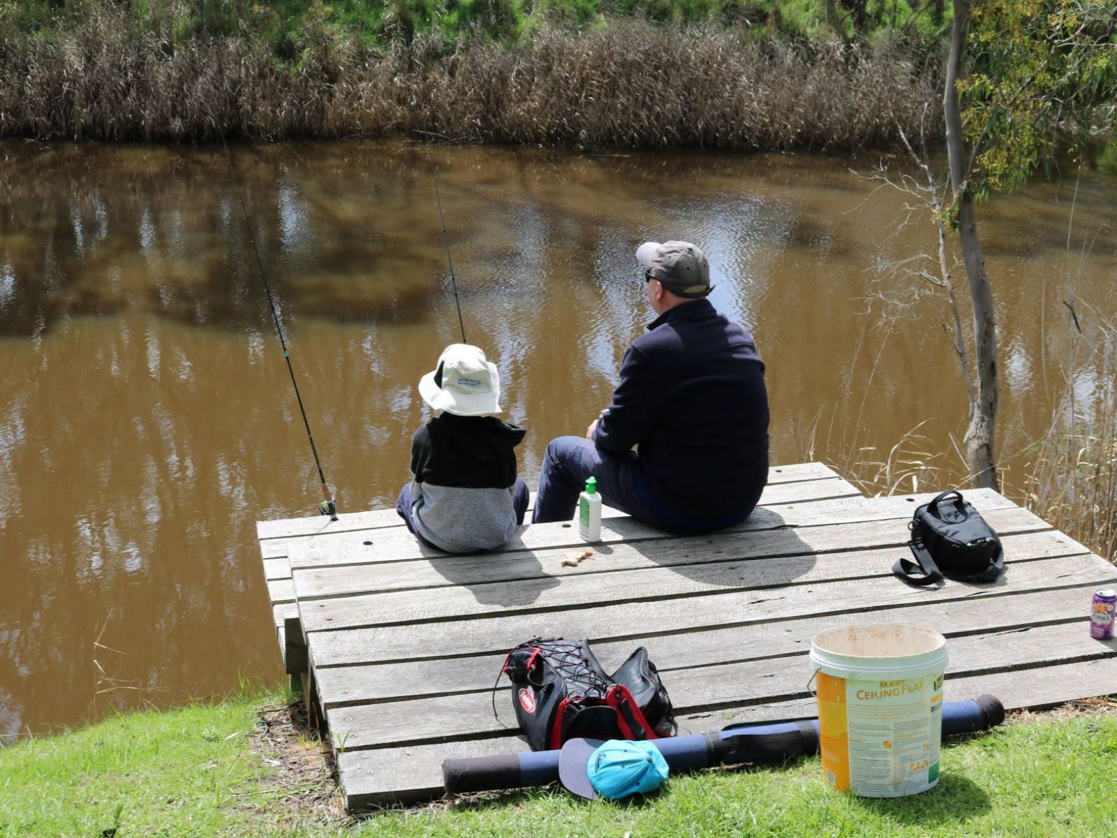 Picture of a man and child with fishing rods sitting on a pier